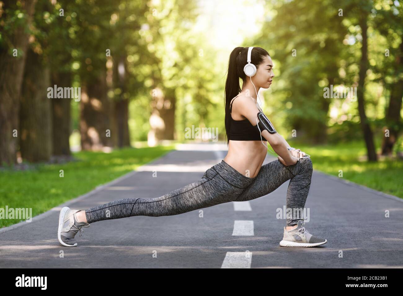 Fit Lifestyle. Sporty Asian Woman Exercising Outdoors In Park, Stretching Leg Muscles Stock Photo
