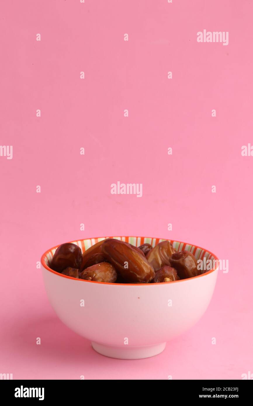 Vertical closeup of a bowl of fruits similar to raisins called dates