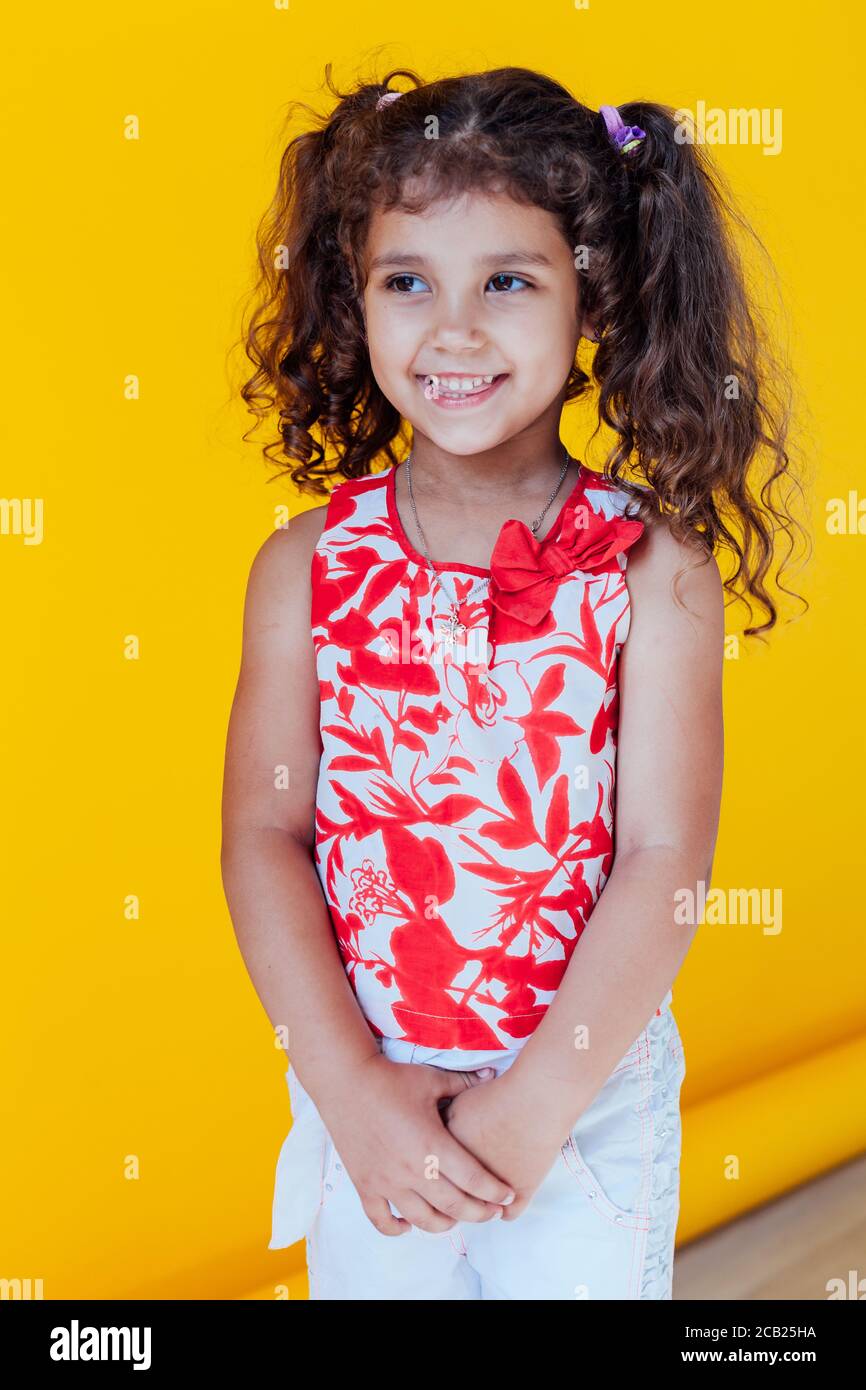 Portrait of a beautiful little fashionable girl with braids on a yellow background Stock Photo