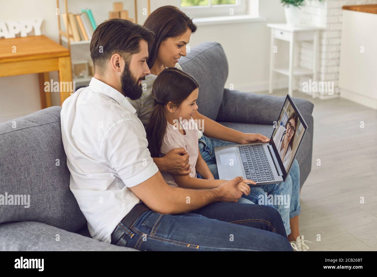 Family doctor online. Happy family consults using video conference computer at home. Stock Photo