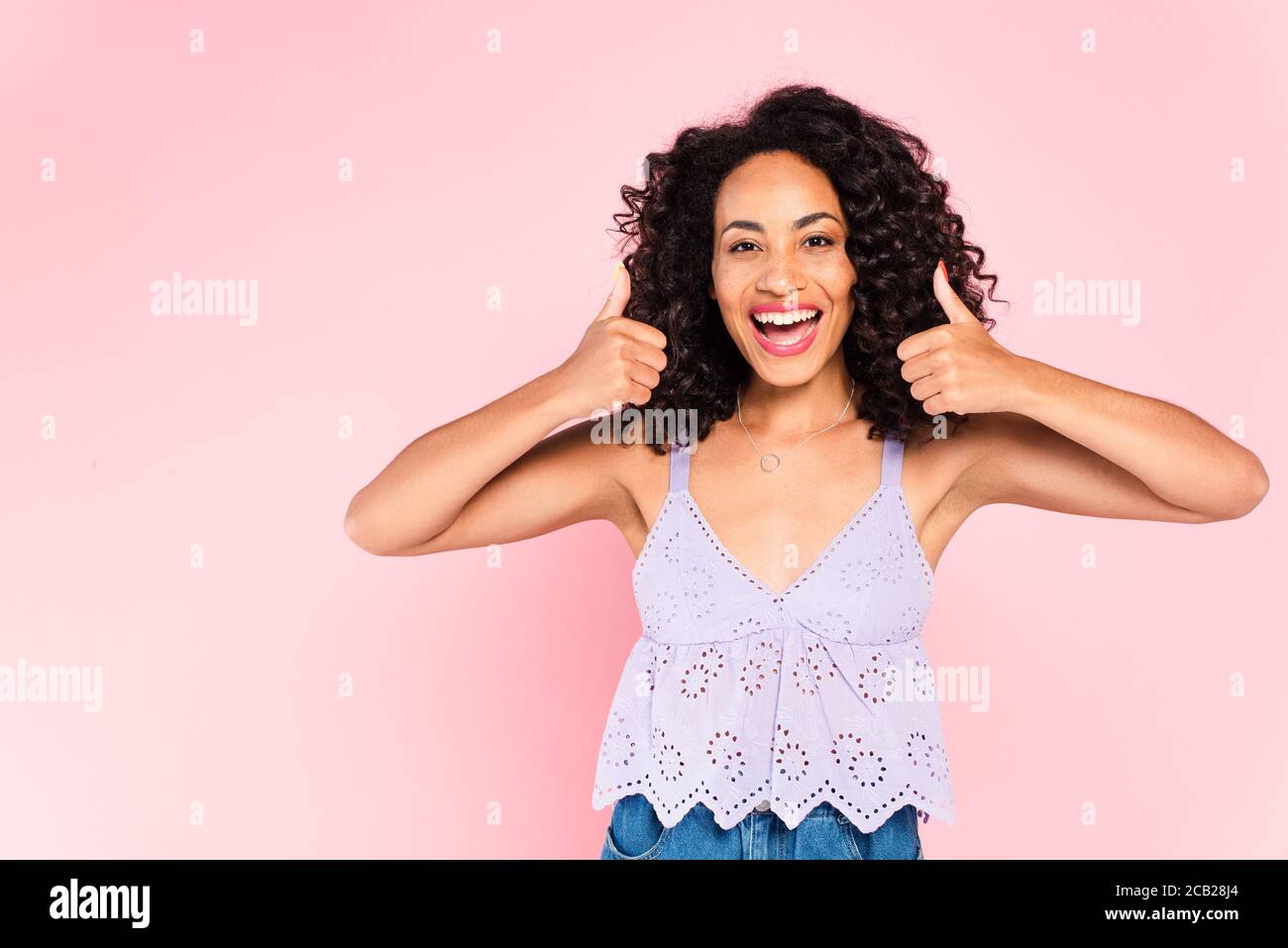 excited african american woman showing thumbs up on pink Stock Photo ...