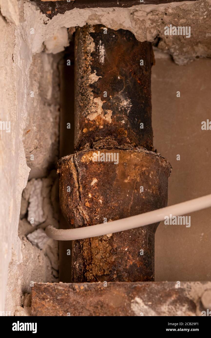 Rusted builtin old cast iron sewer pipe damaged with a crack Stock