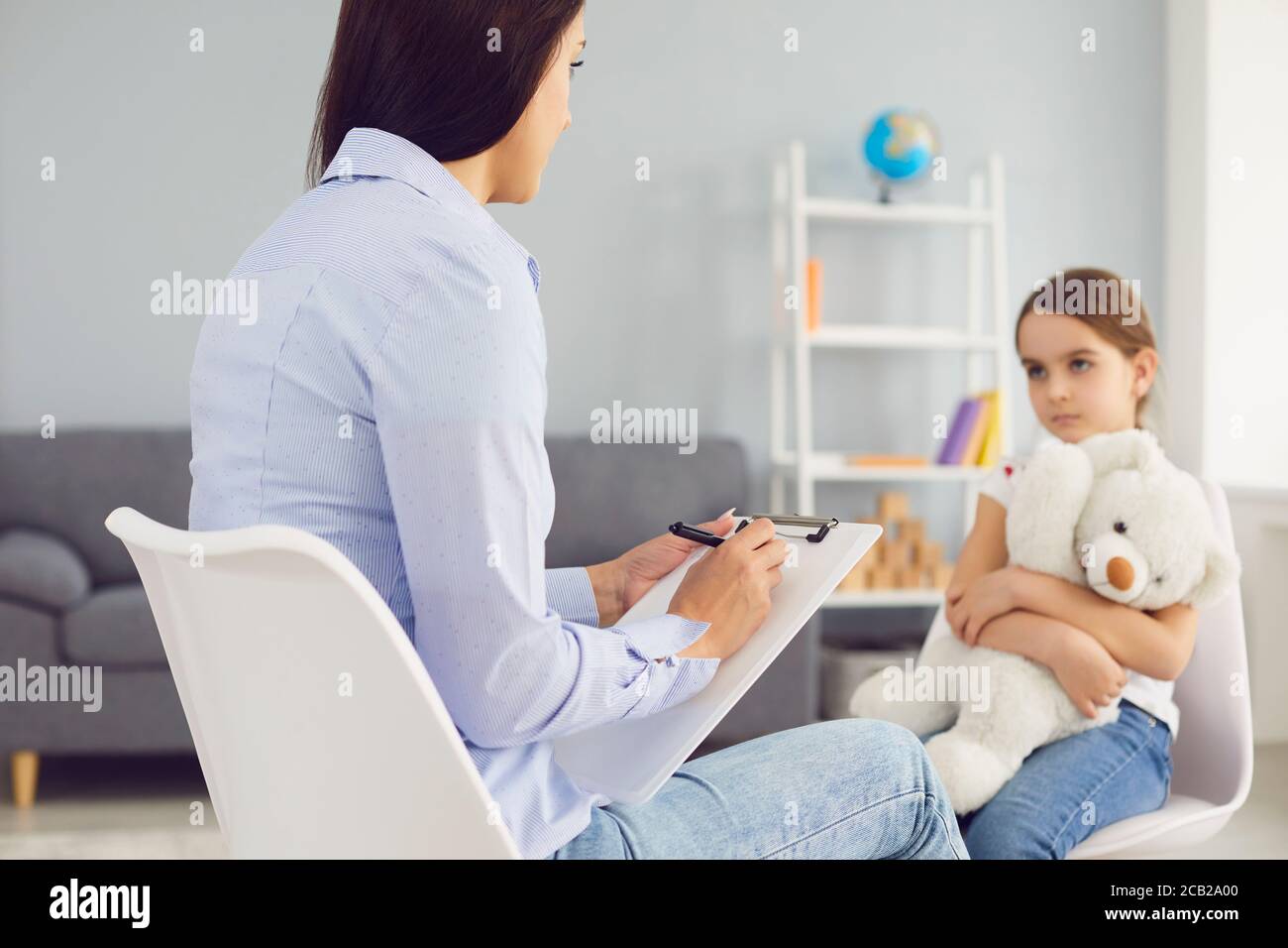 Young Psychologist is talking with a child in the room. Stock Photo