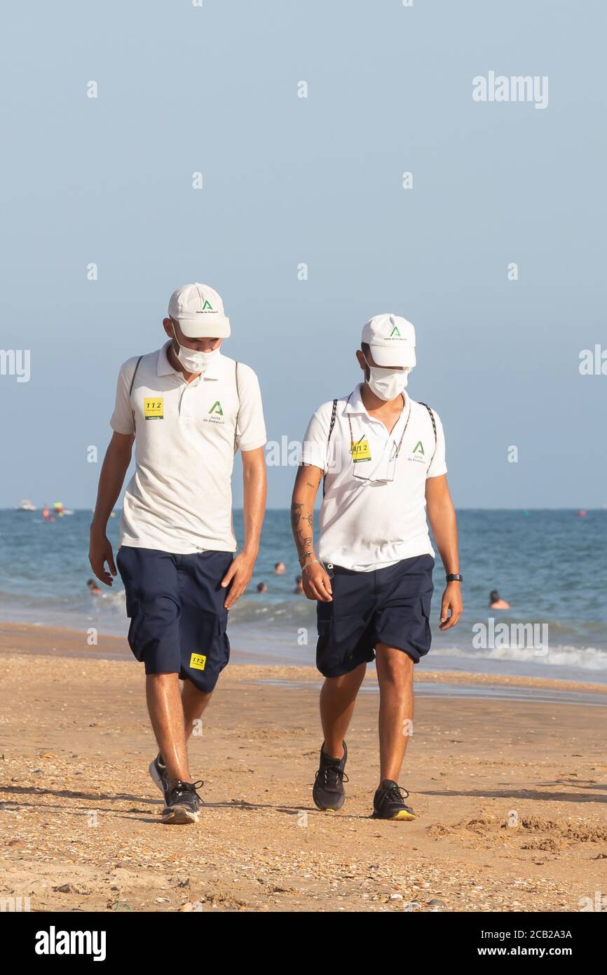 Punta Umbria, Huelva, Spain - August 7, 2020: Beach safety guard of Junta de Andalucia is controlling the social distancing and use of protective mask Stock Photo