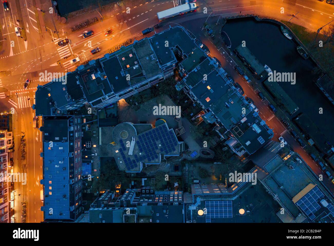 Aerial top view of night european city with buildings roofs and illuminated roads with cars. Stock Photo