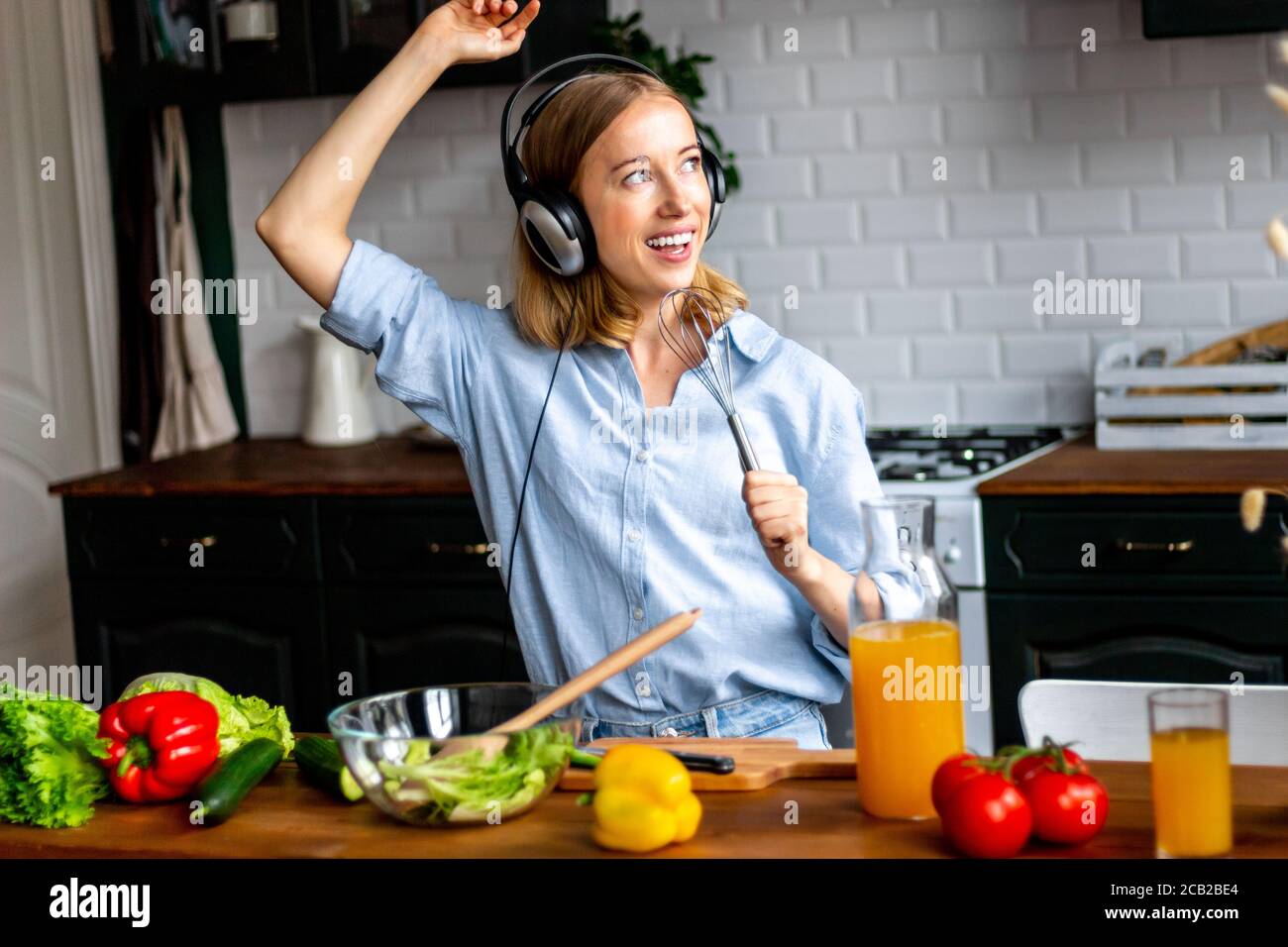 Dancing woman in headphones in kitchen cooking healthy vegetables Stock Photo Alamy