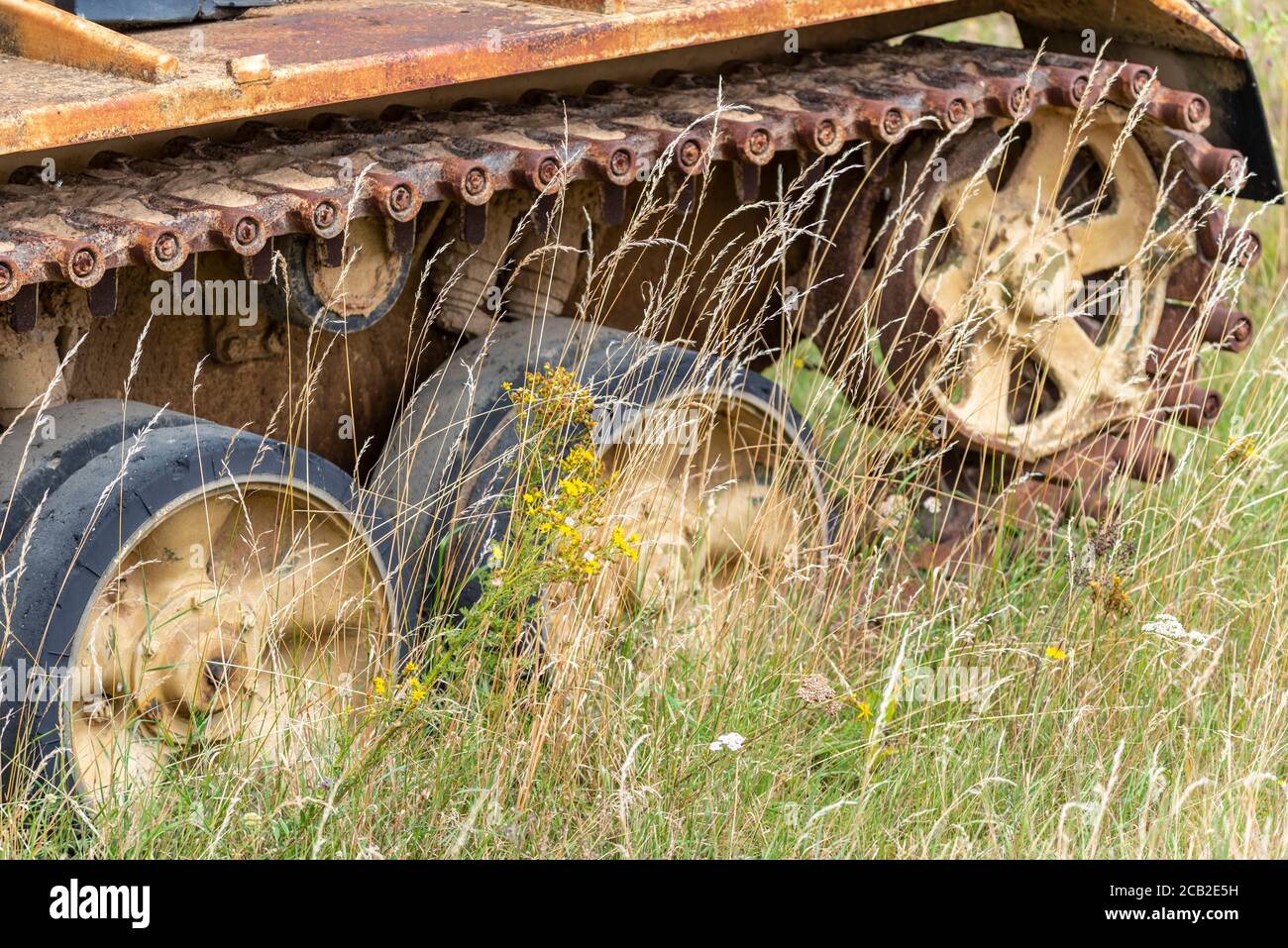 Corroding tank at Imperial War Museum, Duxford, Cambridgeshire, UK. Armoured fighting vehicle, AFV, in long grass. Out to grass. Tank tracks Stock Photo