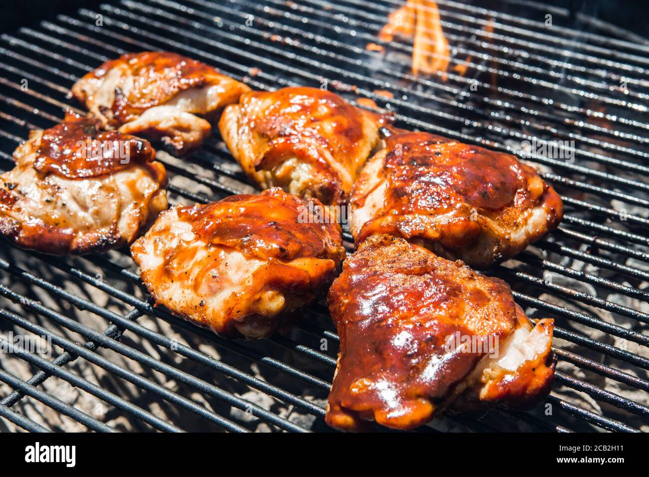Marinated Chicken thighs glazed with a barbecue sauce cooking on a