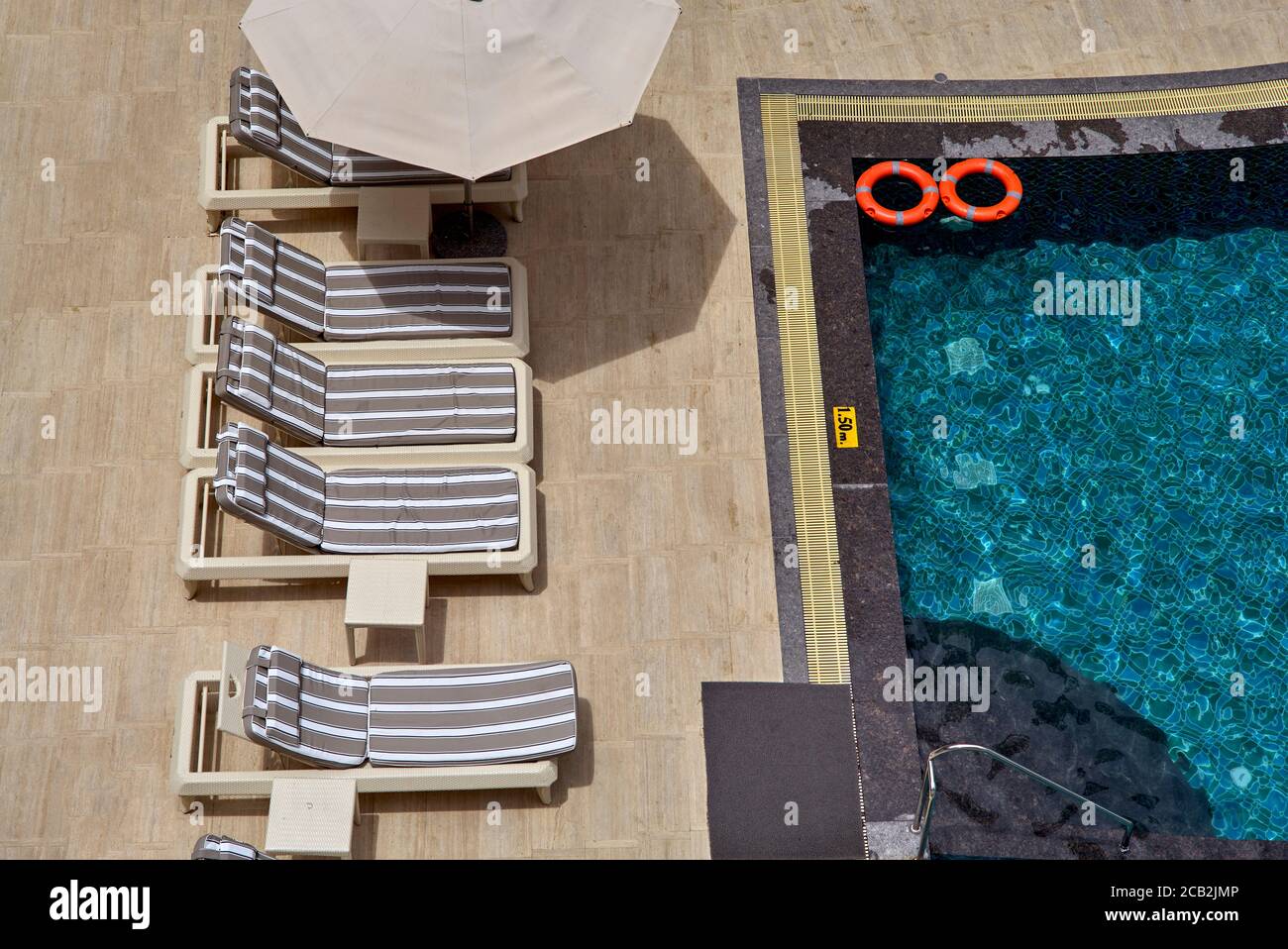 Swimming pool from above with sun bed recliners and umbrella Stock Photo