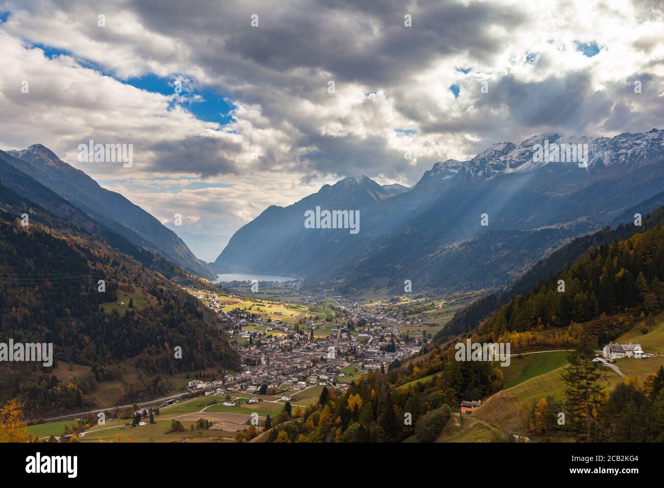 Stunning aerial panorama view of Poschiavo town in valley with Swiss Alps and Lago di Poschiavo lake in background, in autumn on sightseeing railway l Stock Photo