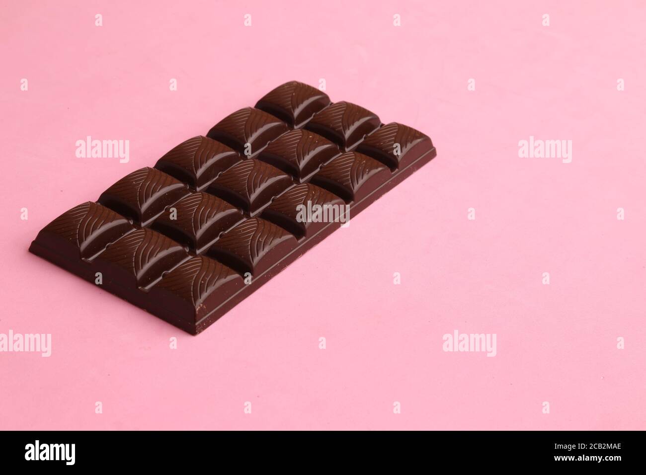Closeup of a chocolate block placed in a slanted angle on a pink