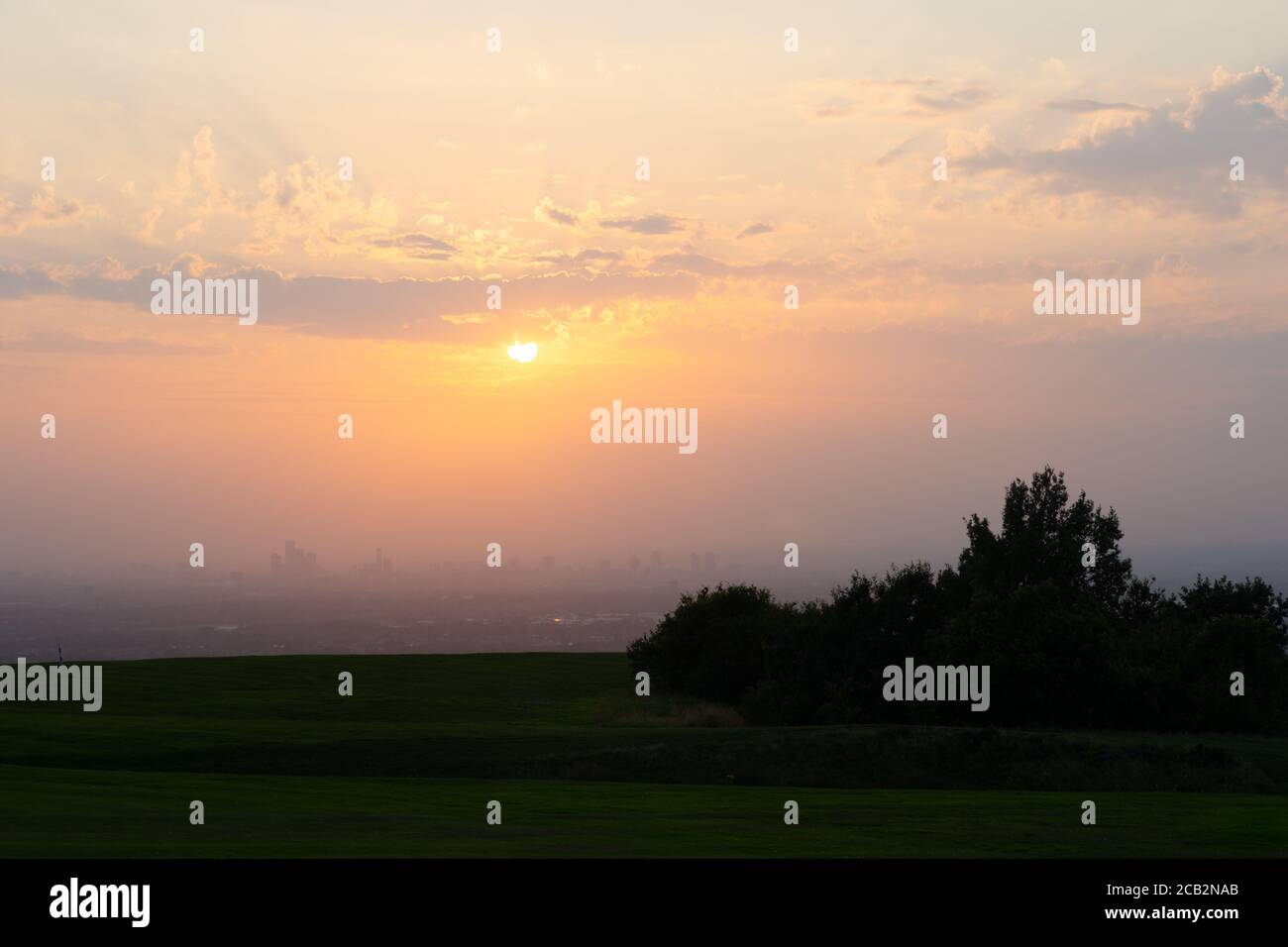 Sunset over Manchester city from Werneth Low golf course. The poor air visibility and clouds helped produce a spectacular deep orange red sunset. UK Stock Photo