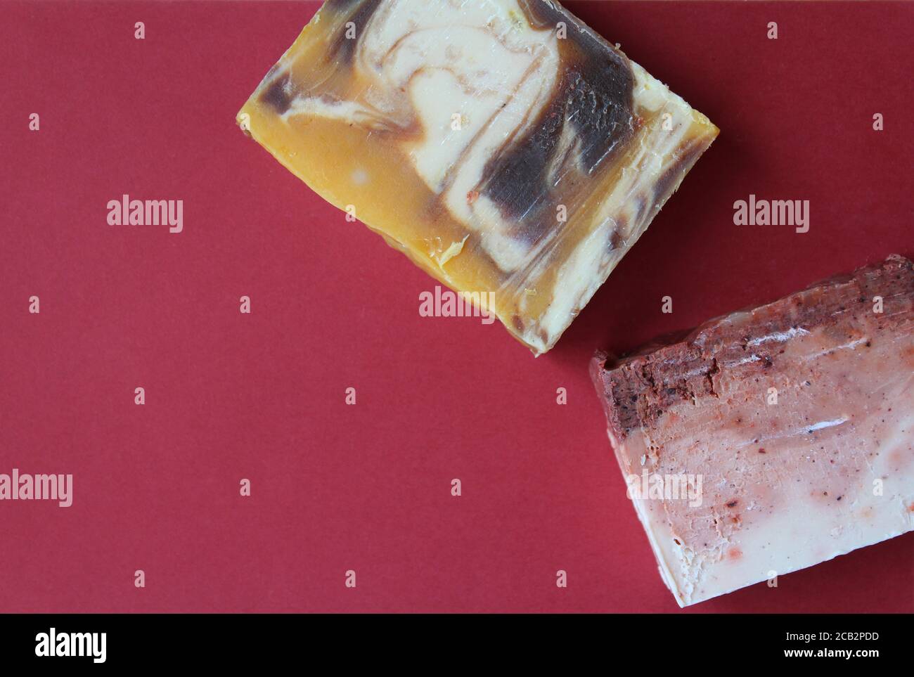 Flat lay blocks of home made soap on a dark red background. Hand made soap with natural ingredients concept, high angle view. Copyspace below left. Stock Photo
