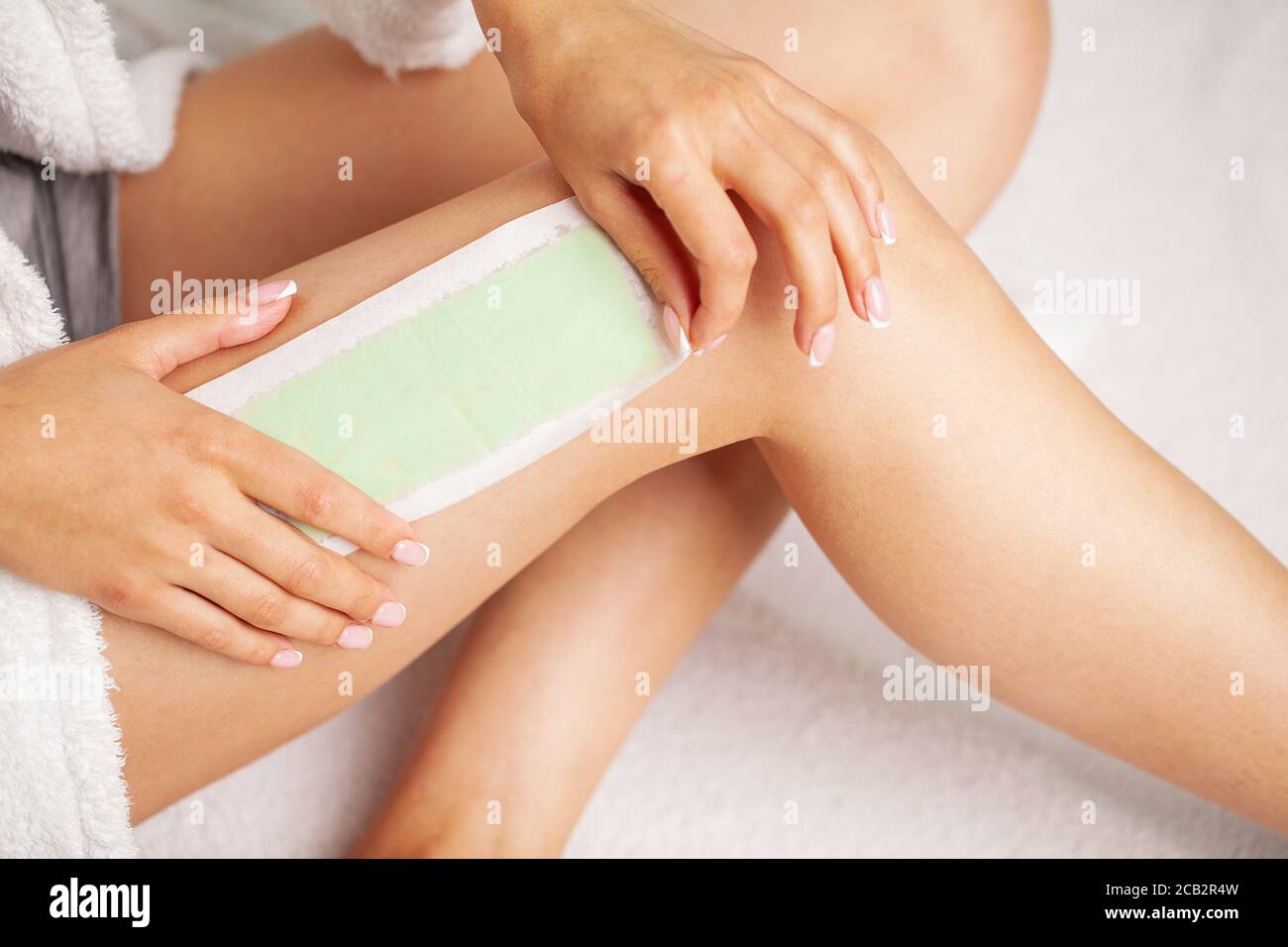 Waxing woman leg with wax strip at beauty spa Stock Photo Alamy