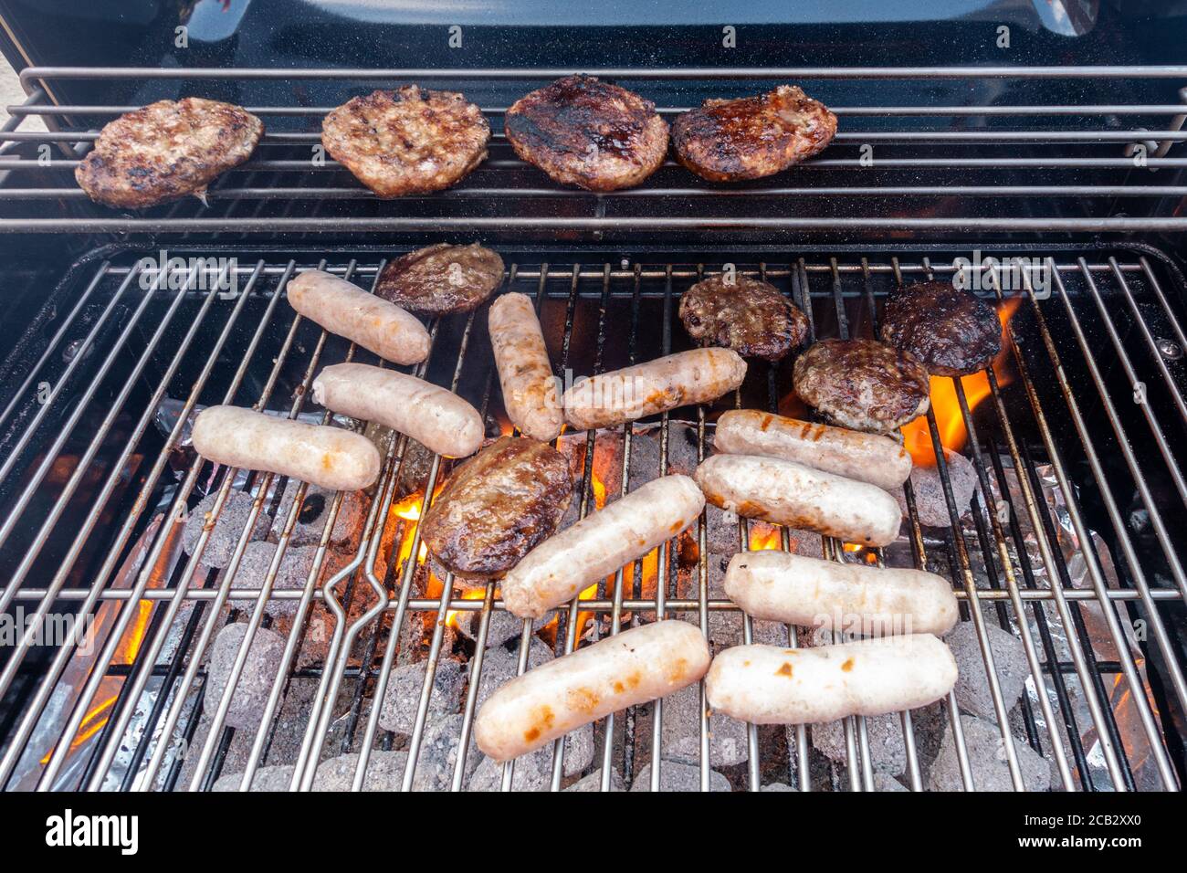 Sausage and beef burgers cooking on a barbecue Stock Photo Alamy