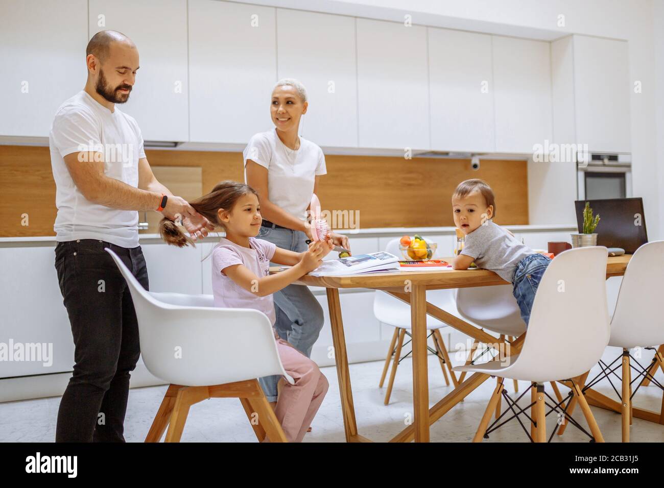 Caucasian family in white kitchen with modern interior taking meal ...