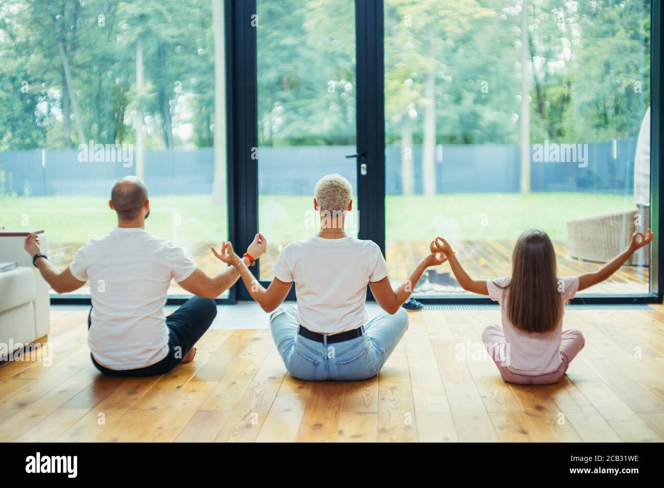 Back of Fit healthy family sitting in lotus pose on floor at home. Yoga ...