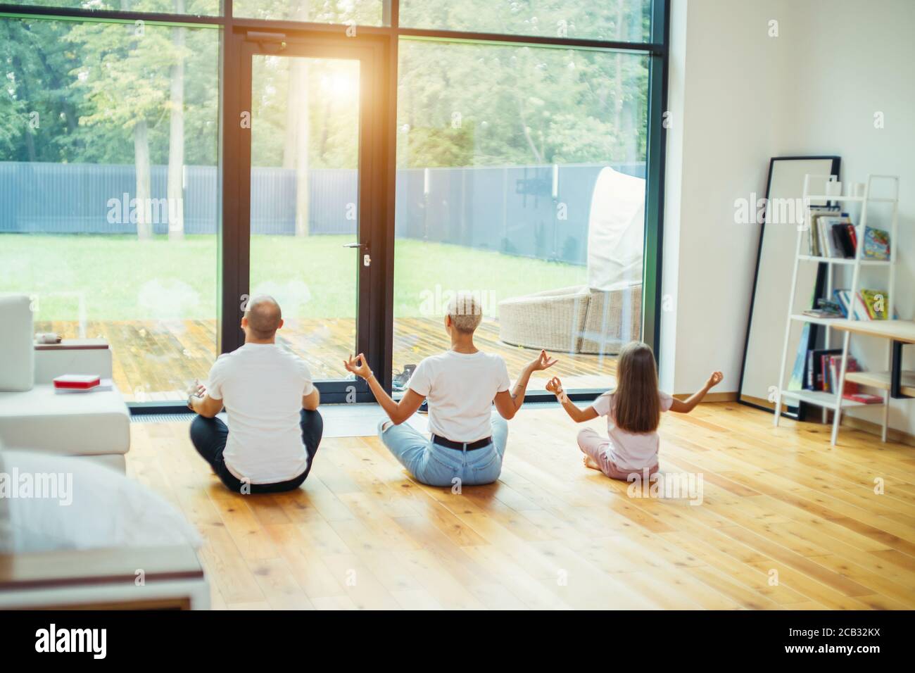 Fit healthy family sitting in lotus pose on floor at home. Yoga with ...