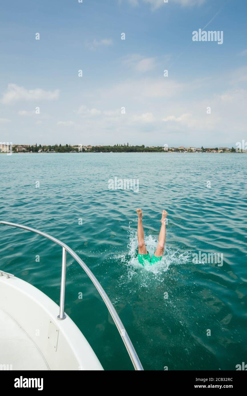 boy is jumping an diving from a boat into turquoise water, lake Garda,  italy Stock Photo - Alamy