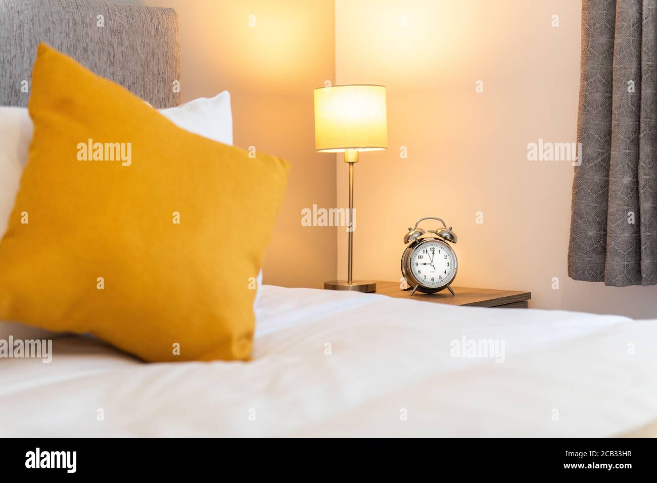bedroom with yellow pillow and alarm clock Stock Photo