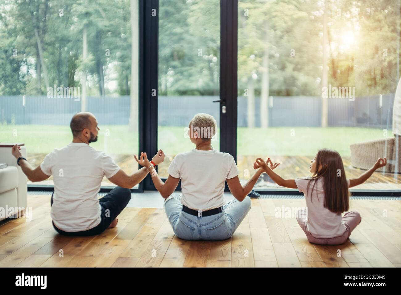 Fit healthy family sitting in lotus pose on floor at home. Yoga with children at home Stock Photo