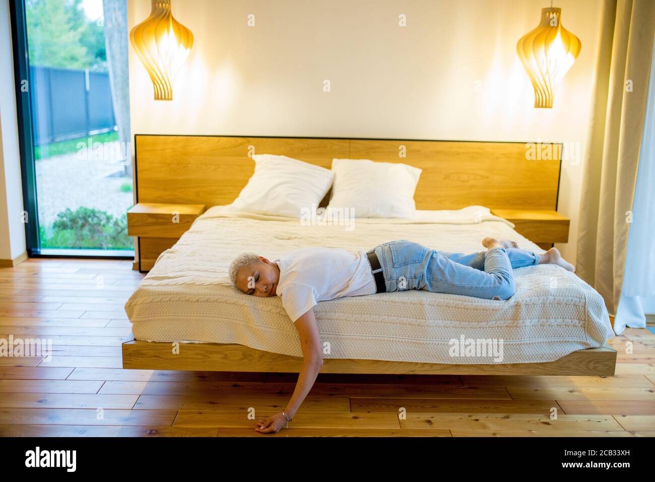 shorthaired female lying on the edge of bed after work. With lowered