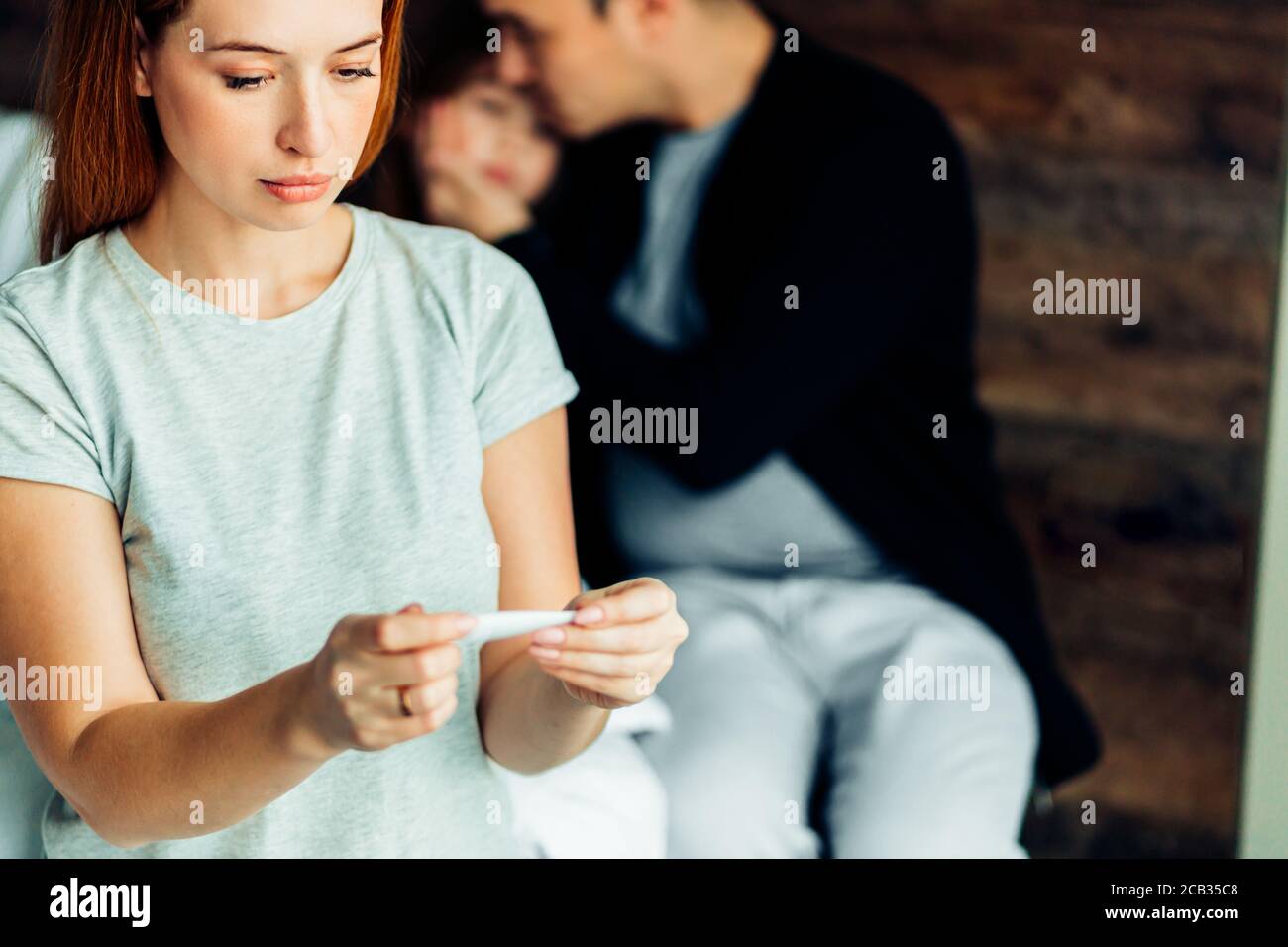family concept. caucasian woman check temperature of sweet daughter suffering from cold at home, lying on bed with careful mother and father Stock Photo