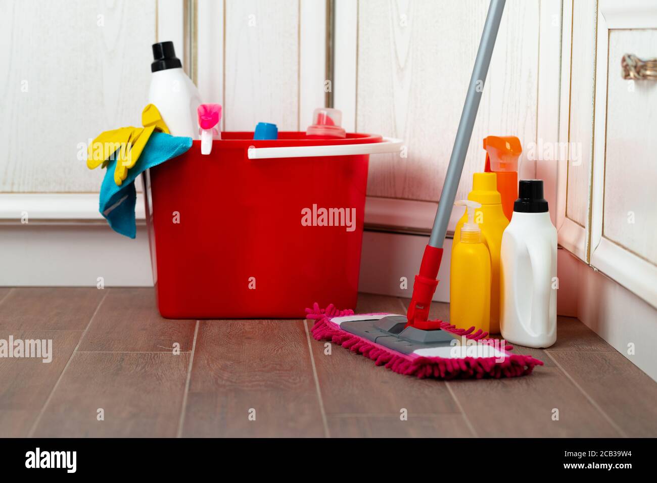 Various household cleaning detergents and bottles in a plastic bucket ...