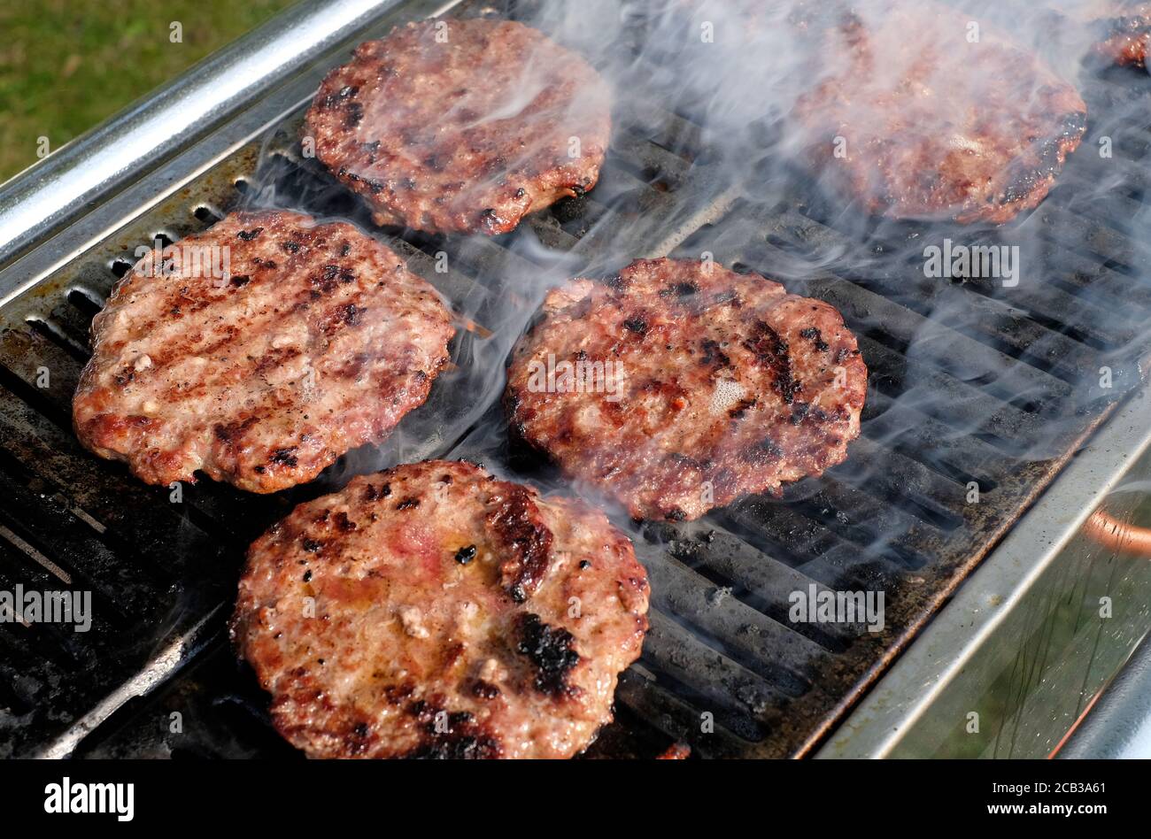 sizzling beefburgers cooking on barbecue grill Stock Photo - Alamy