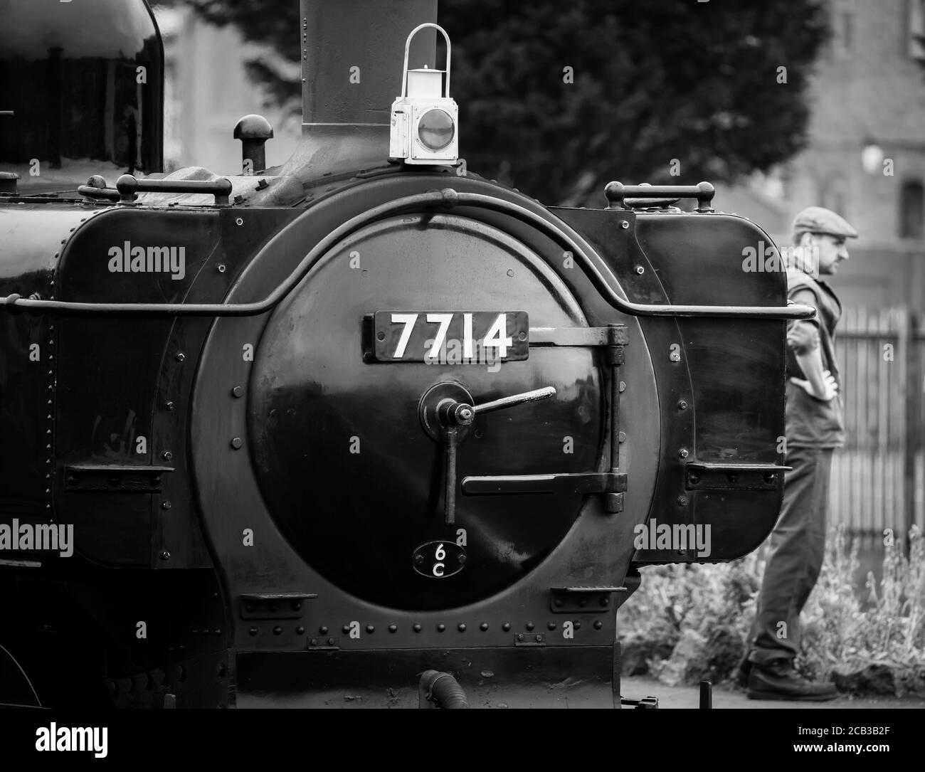 Monochrome close up of vintage UK steam locomotive front standing by platform, Severn Valley Railway Kidderminster, with waiting steam train driver. Stock Photo