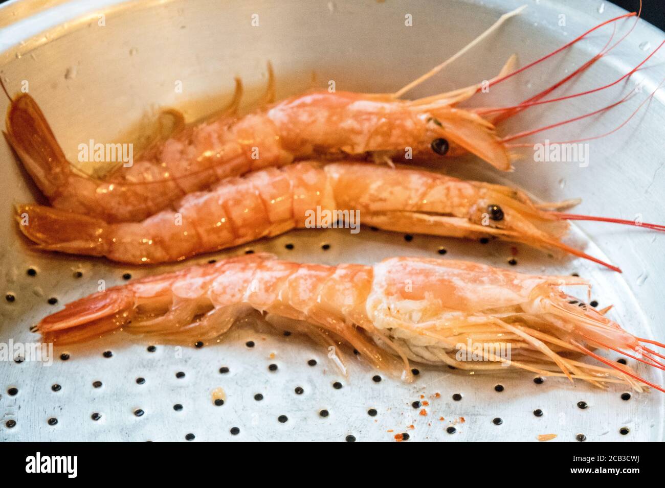 Nice sized prawns in a prep bowl ready for cooking.  Lovely color in the prep bowl with water residue. Preparation for a lovely seafood serving Stock Photo