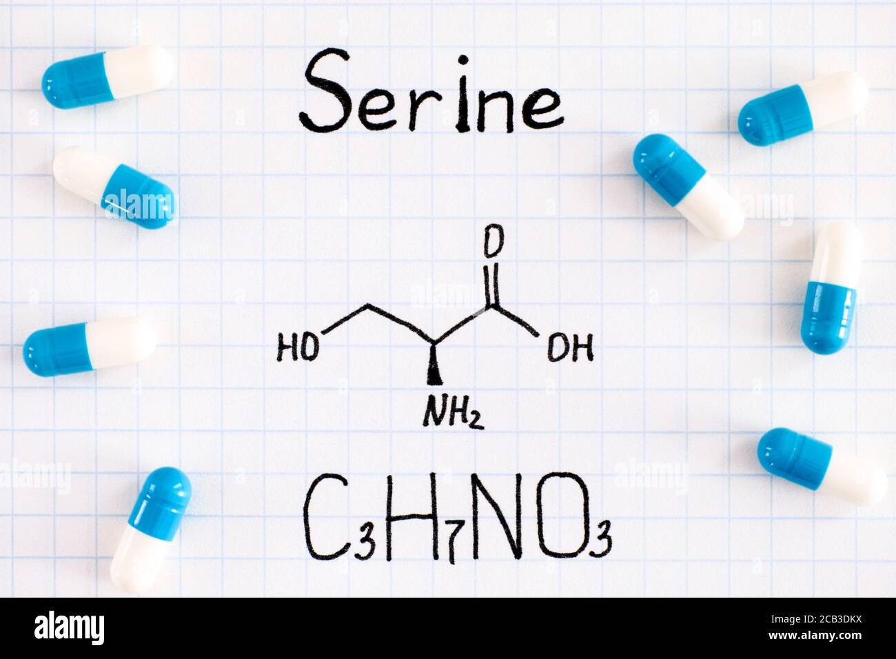 Chemical formula of Serine with some pills. Close-up. Stock Photo