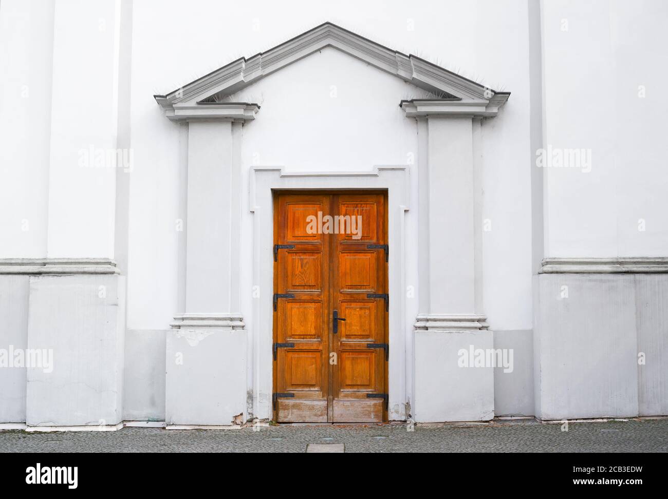 Wooden door and entrance into old historical building. White architecture is made in classicist architectonic style. Symmetrical central composition Stock Photo