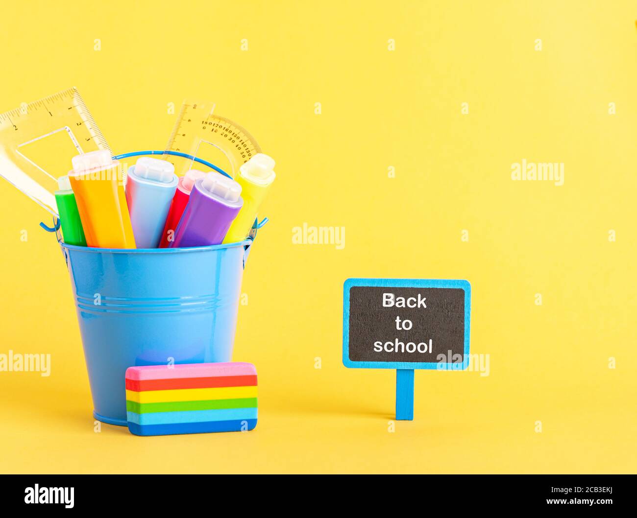 A metal bucket with highlighter marker pen and school ruler on a blue background. Stock Photo