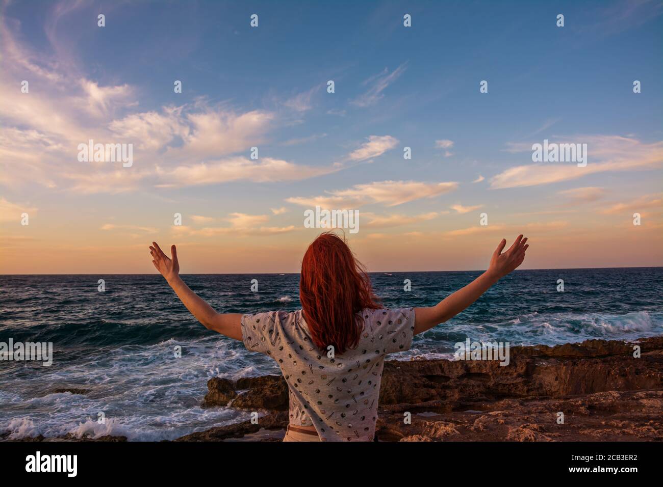 A young girl open arms under the sunset at seaside, Freedom and happiness Stock Photo