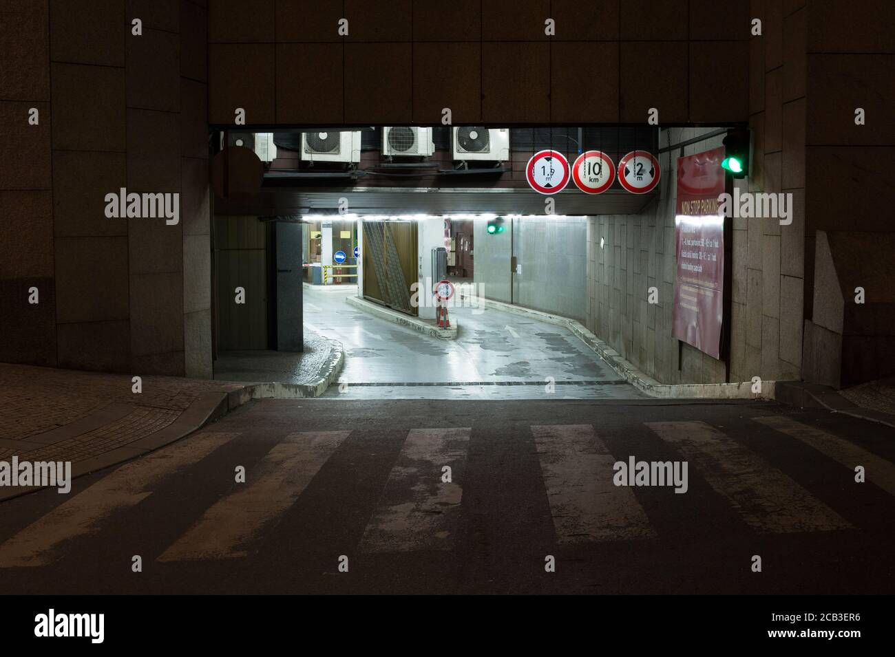 Entrance to underground car park at night. Outdoor area is dark, carpark is lit by artificial light. Stock Photo