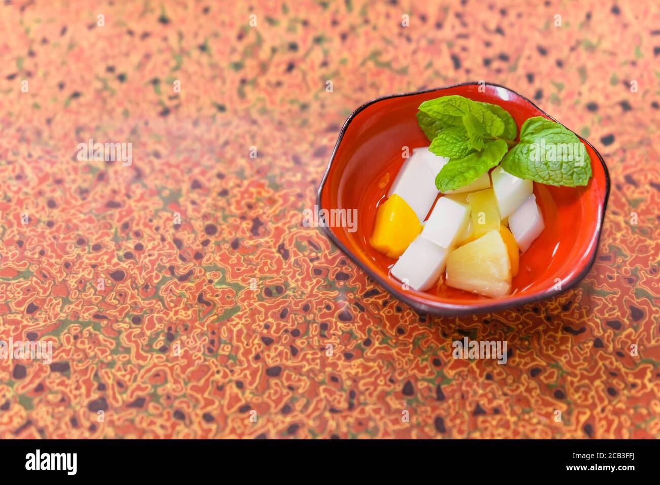 Japanese traditional dessert of Annin tofu or almond tofu made of apricot kernel milk, agar, and sugar with fruits pieces like pineapples and apricot Stock Photo