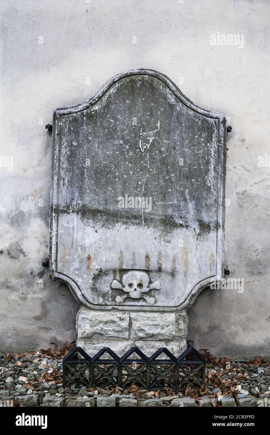 Old gravestone made of stone. Symbol of skull and crossbones is on the