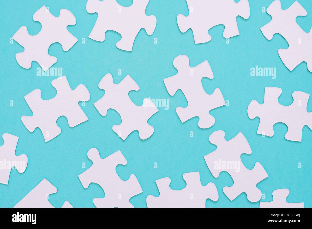 White puzzle pieces scattered on a blue background Stock Photo