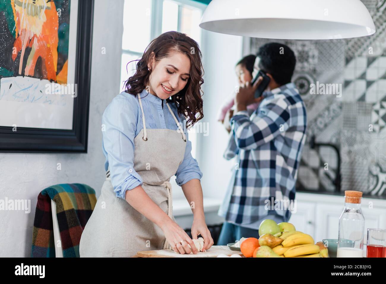 attractive housewife making salad for family while her husband having a chat, close up photo. Stock Photo