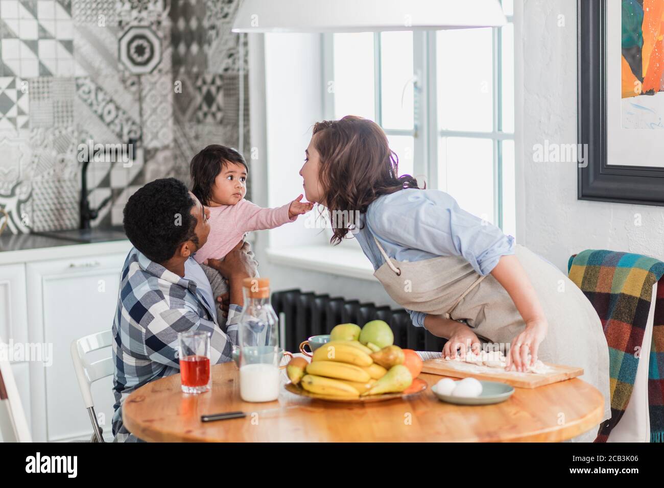 mom is kissing her little pretty daughter while preparing meal, close up photo. family tradition, custom Stock Photo
