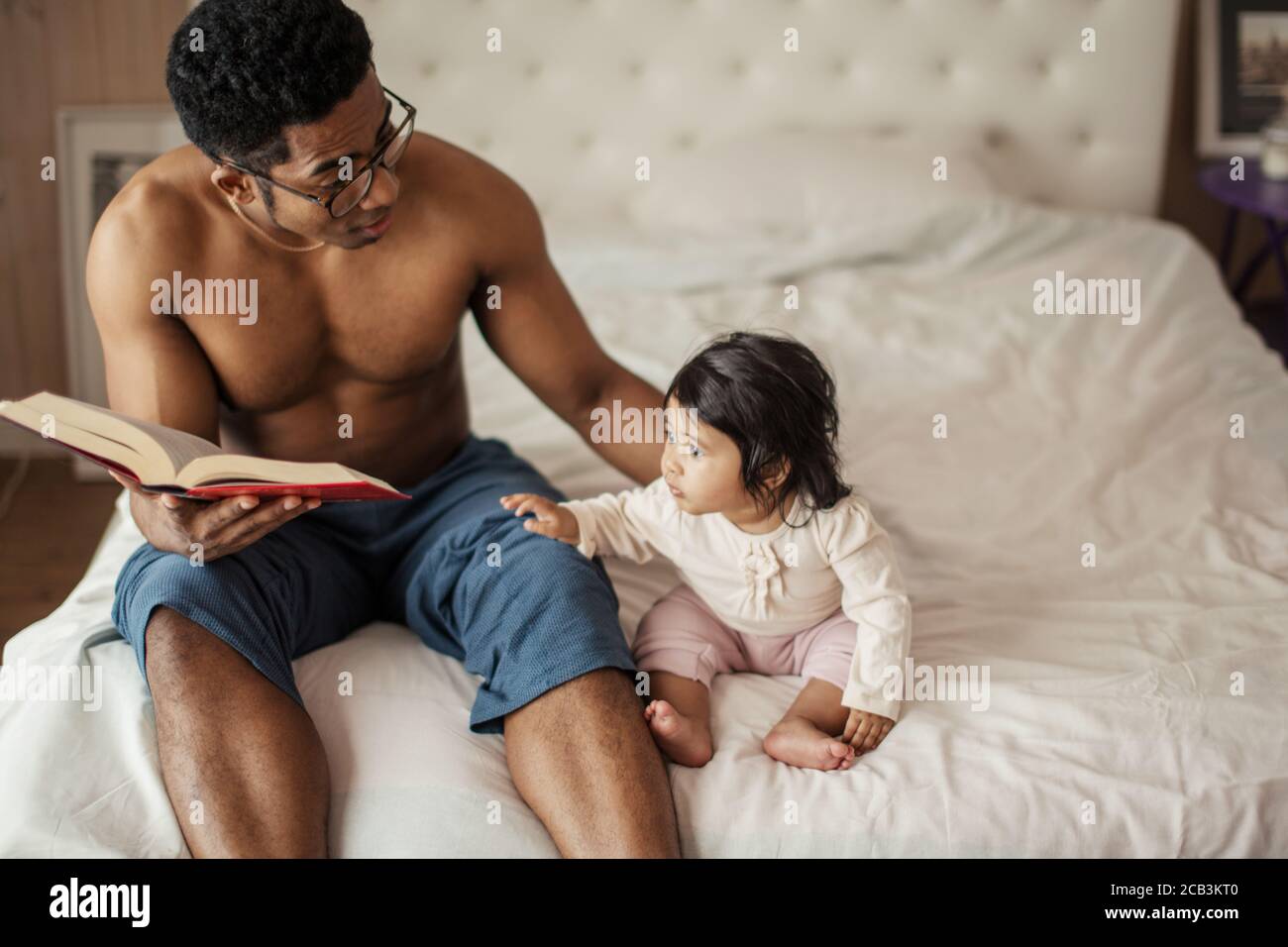 beautiful little girl listening to dad reading fairy tale while resting in the bedroom. close up photo, copy space, interest, lifestyle Stock Photo