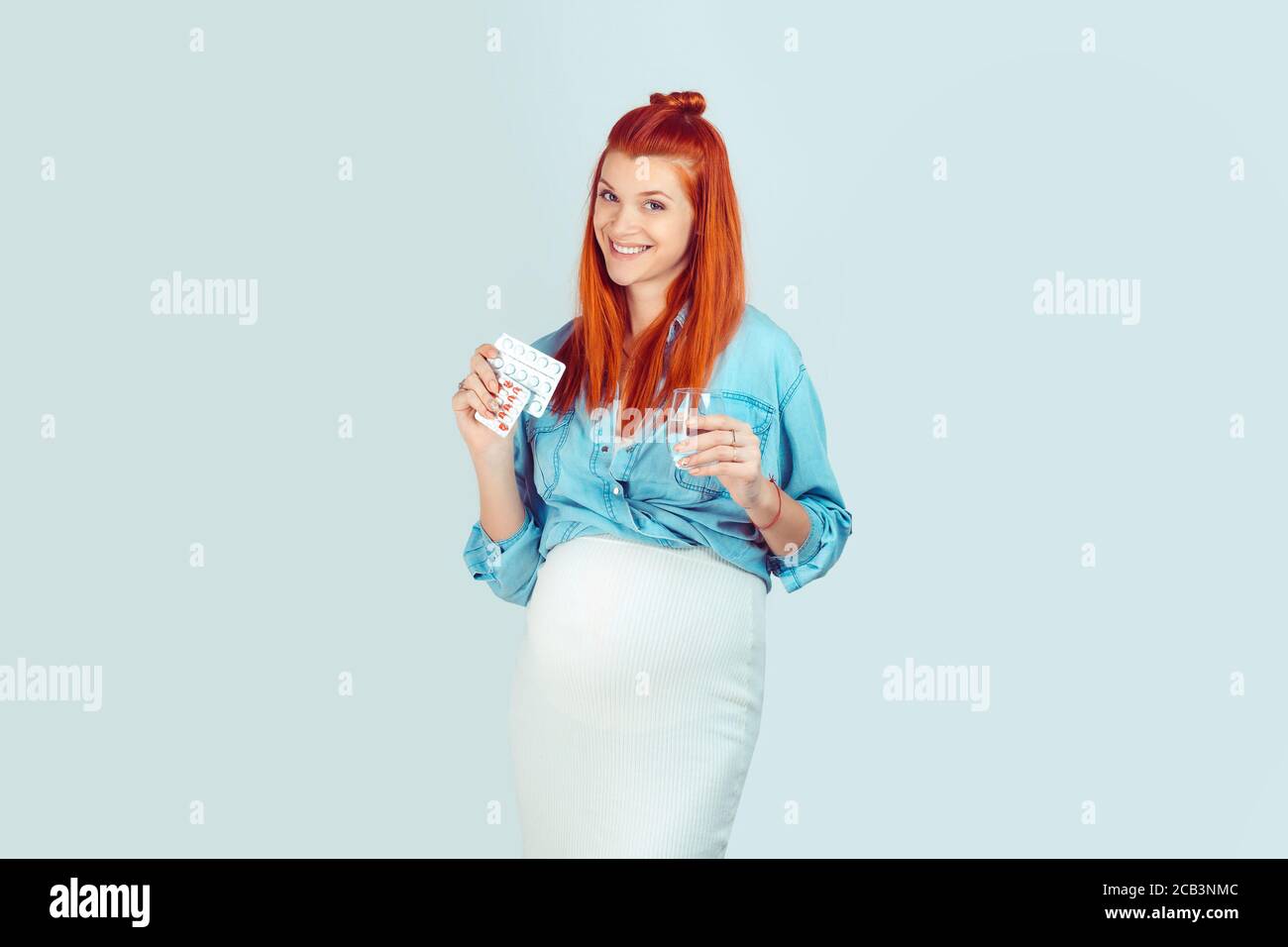 Don't forget about your pills, vitamins, minerals, supliments. Wonderful young model with glass of water and pills for pregnant smiling at camera happ Stock Photo