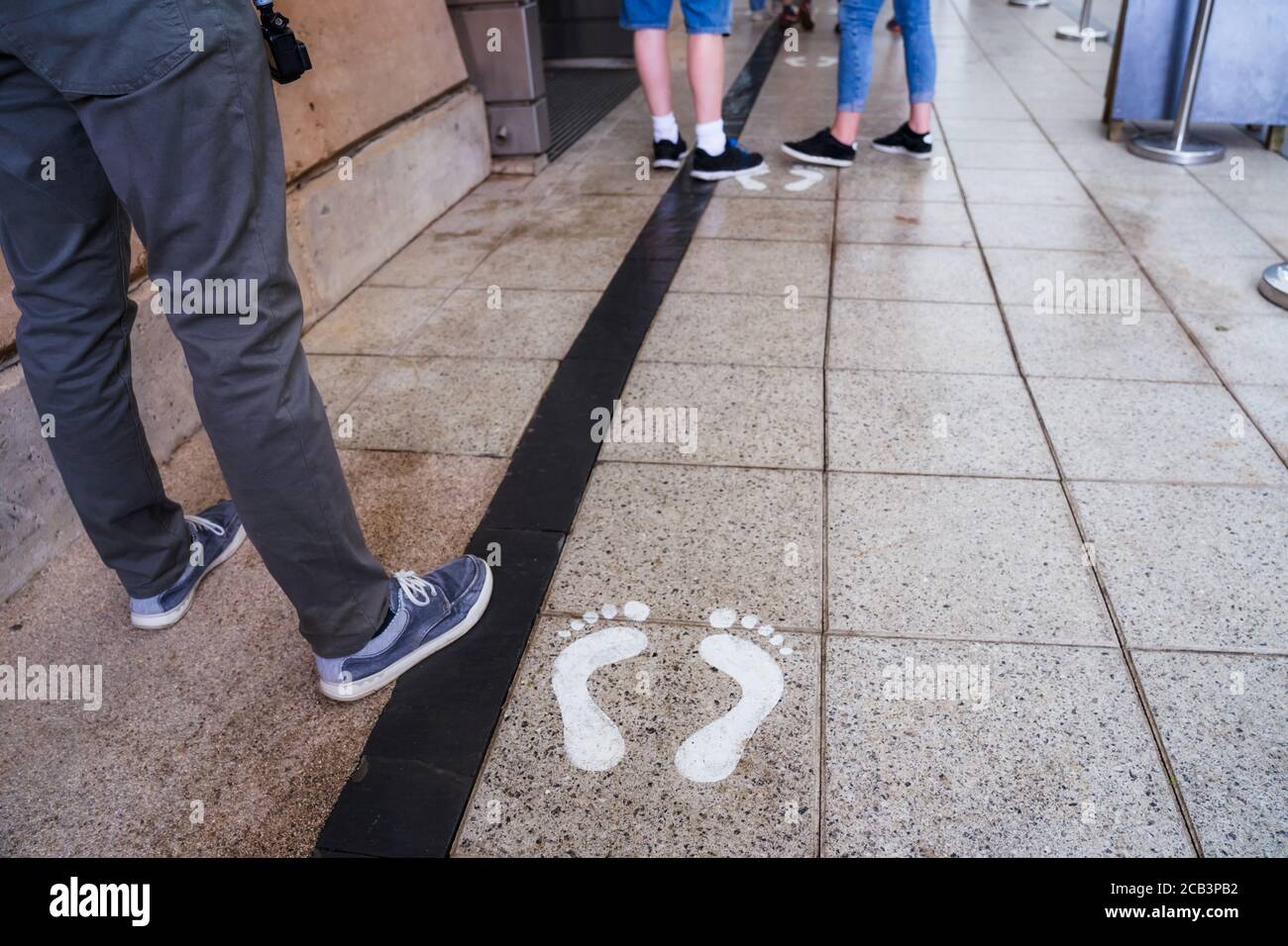 Feet of person taking queue in social distance queue to enter to prebooked tourist place. New normal tourism practices for visiting public places duri Stock Photo