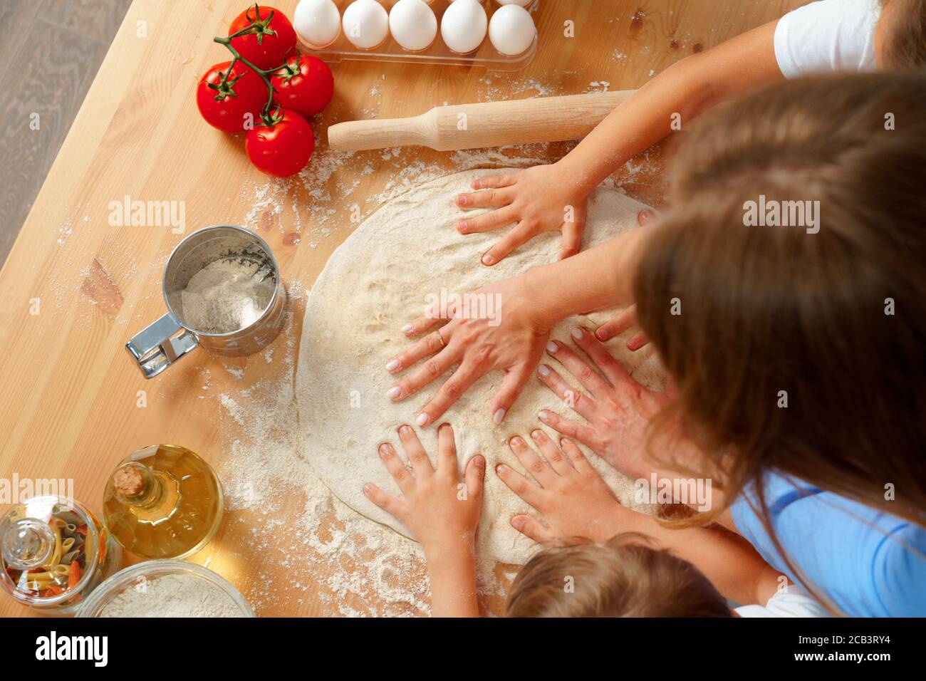 Mother and her kids kneading dough on kitchen table Stock Photo - Alamy