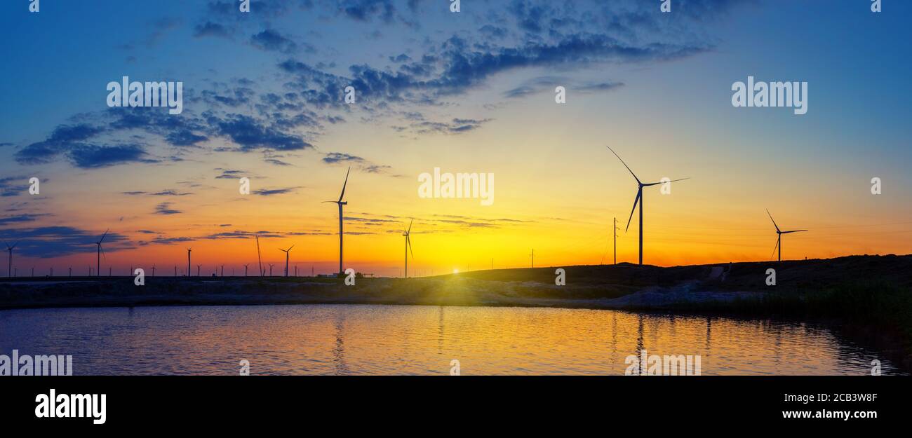 Silhouettes of wind generators power plant on lake at sunset Stock ...