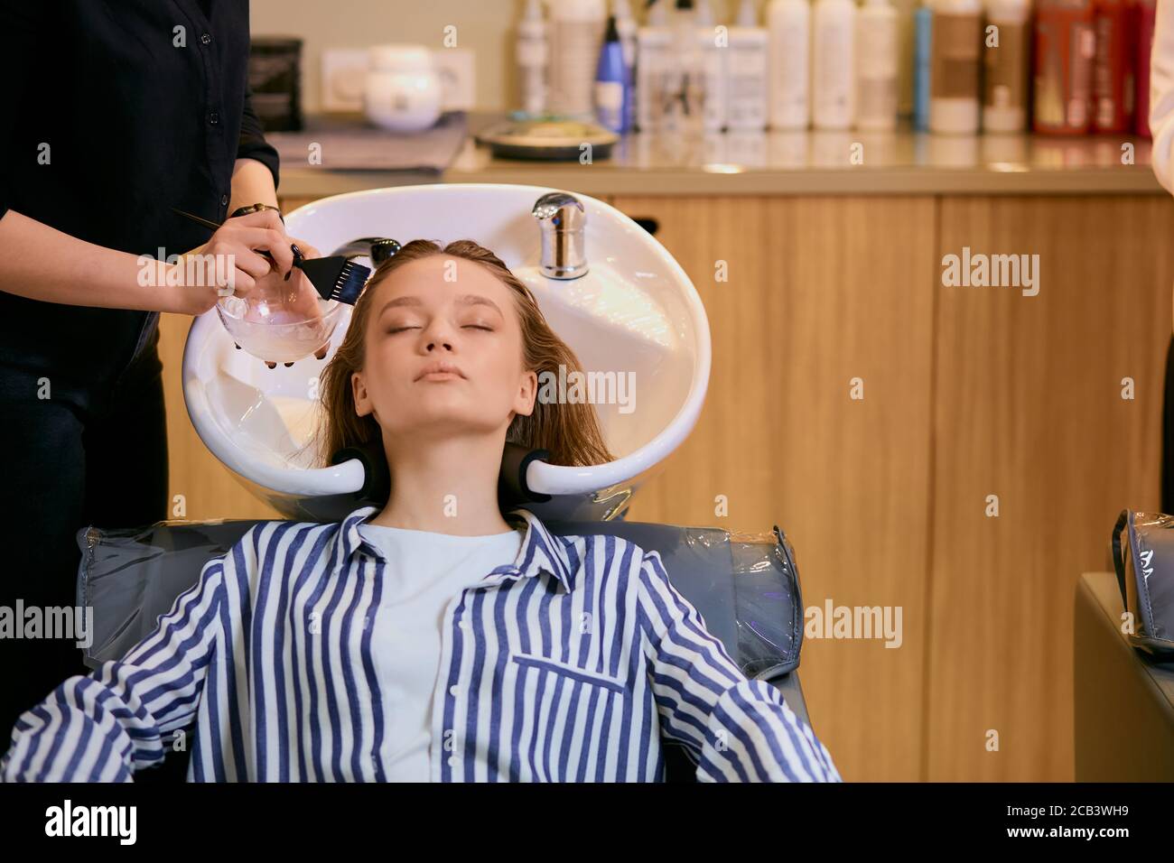 young beautiful woman dyeing hair in modern beauty saloon, professional hairdresser wash and dye woman's hair Stock Photo