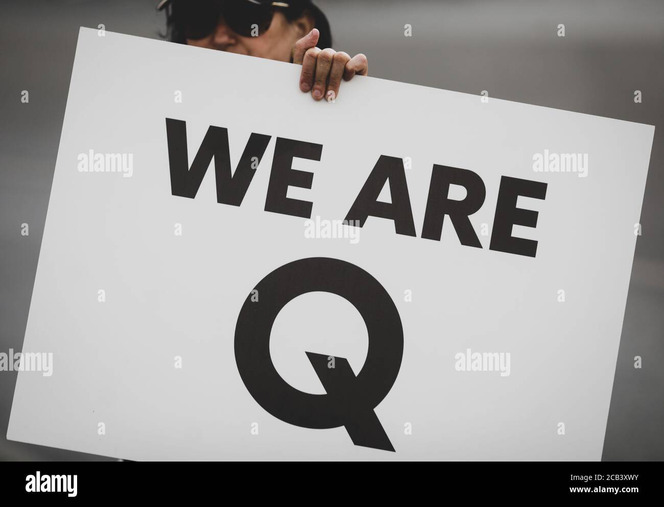 Bucharest, Romania - August 10, 2020: A woman takes part at a protest and displays a Qanon message on a cardboard. Stock Photo
