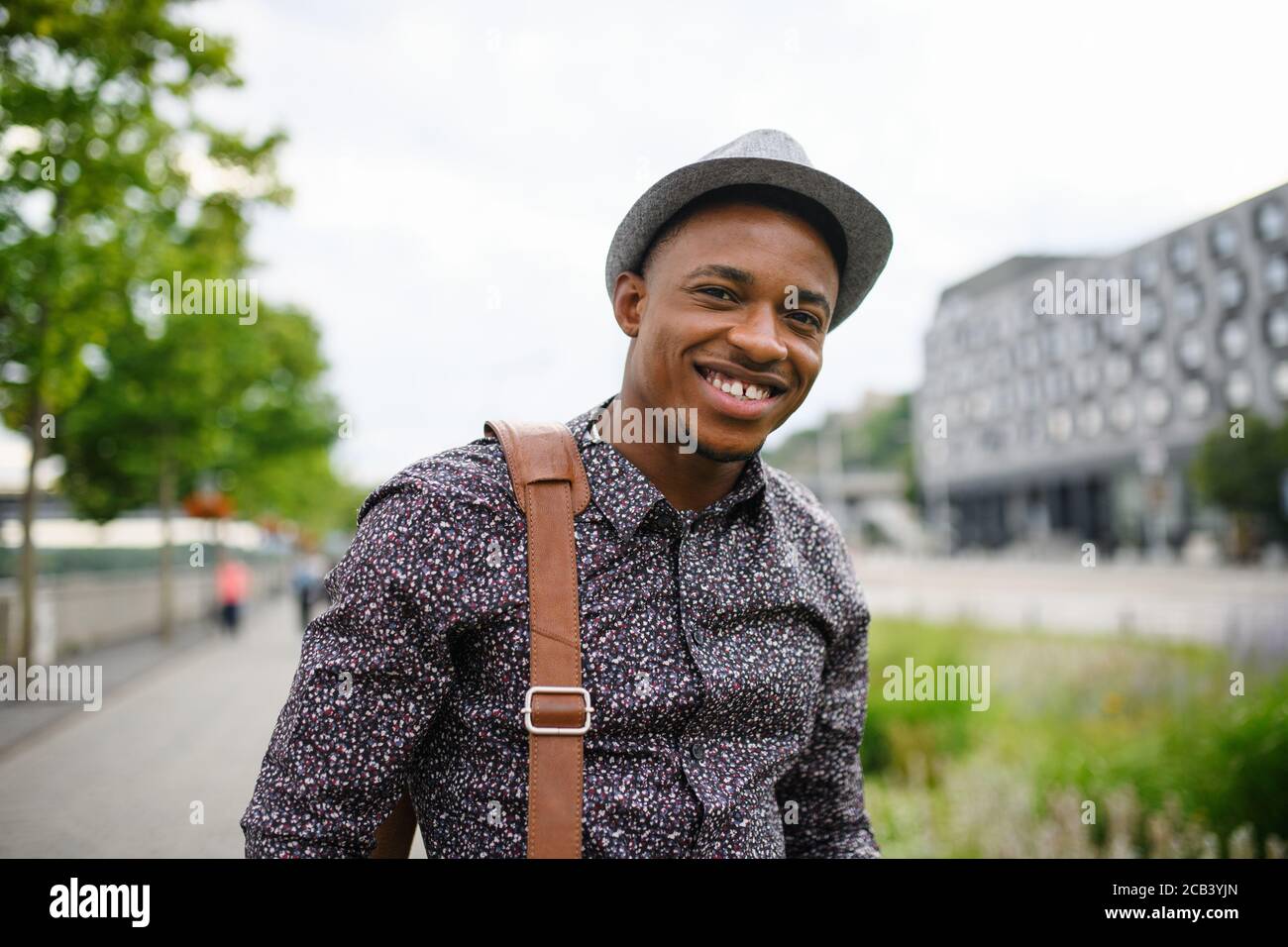Cheerful young black man commuter outdoors in city, walking. Stock Photo