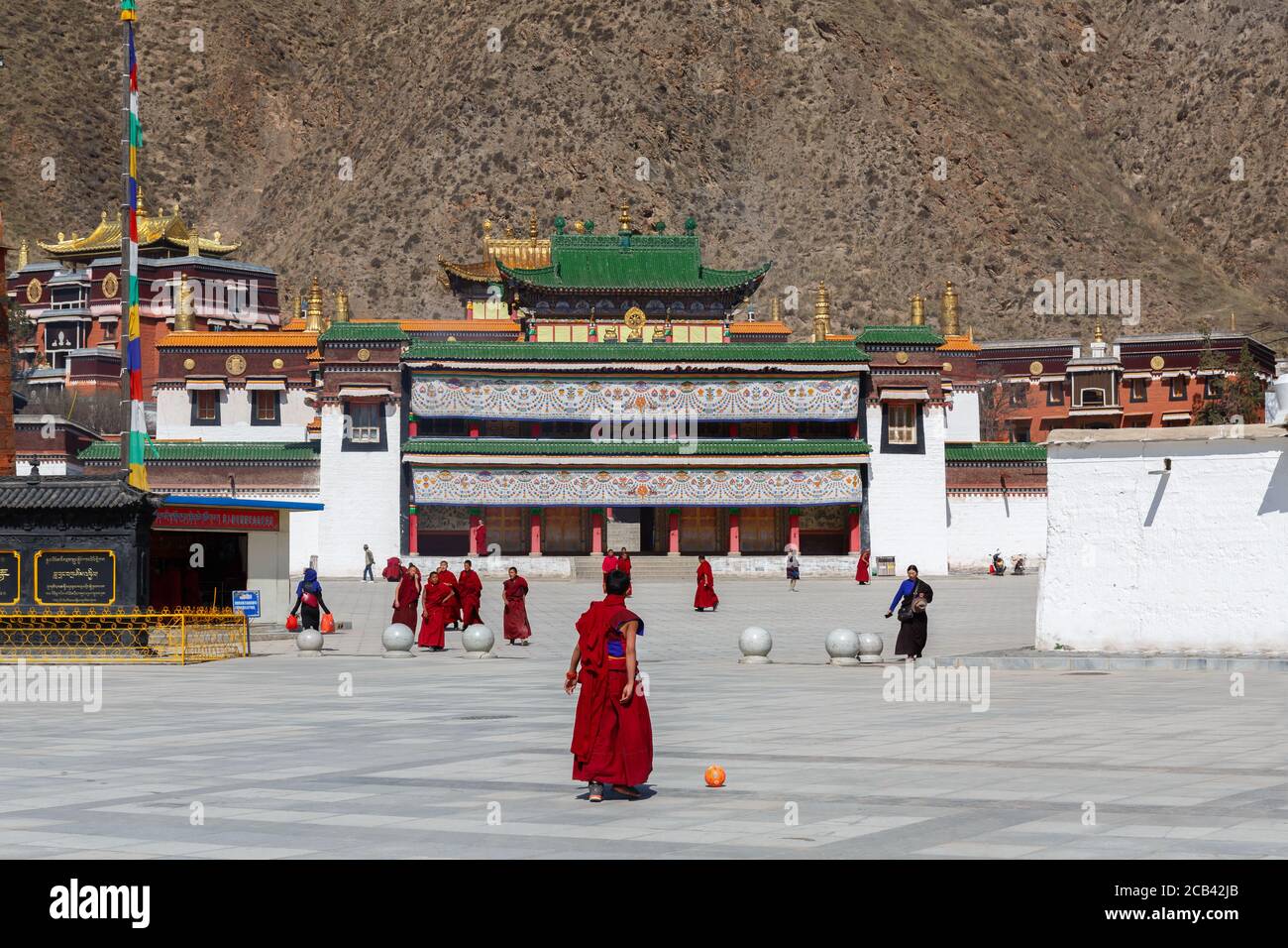 View at a square at Labrang Monastery. With red robed monks. Temple buildings with golden and green roof. Stock Photo